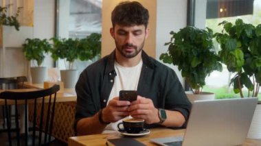 Kafkasyalı mutlu bir adam cep telefonu kullanıyor akıllı telefon işadamı internetteki iş adamı sohbet eden öğle yemeği lokantası erkek ziyaretçi cep telefonu kameraya gülümseyen iş kahvesi kruvasanı.