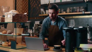 Kafkas girişimci personelin kafe garsonluğunda çalışmasına memnun oldum. Gülümse, kahve iç, enerji iç, adam dizüstü bilgisayarlı restoranda daktilo yazıyor. Erkek barmen eleman internetten küçük işletmeler sipariş ediyor.