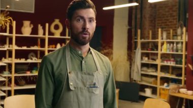Hayretler içerisindeki beyaz erkek satıcı erkek çömlekçi erkek iş adamı küçük işletme sahibi kameraya bakıyor açık ağız şoku inanılmaz haberler içerideki çömlekçi dükkanında