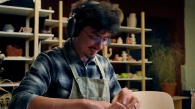 Erkek çömlekçi, seramik atölyesinde kil modelleme yapıyor. El yapımı, el yapımı, tasasız, güler yüzlü, mutlu erkek sanatçı tasarımcısı. Çanak çömlek el işi yapıyor.