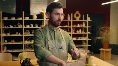 Beyaz, mutlu, gülümseyen satıcı, çömlekçi, erkek, işadamı, sanatçı, küçük iş adamı, vazo satan, seramik çömlek sahibi, dükkan atölyesinden para kazanan müşteriye alışveriş çantası verin.