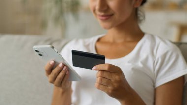 Mutlu gülümseyen Hintli kadın Arap kadın alıcı müşteri güvenli sayıda kredi kartı bankacılığı online cep telefonu alışverişi akıllı telefon satın alma uzaktan satın alma ev ödemeli internet girin
