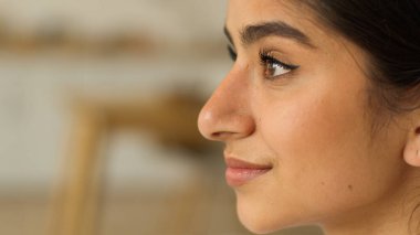 Kadın profili, yan taraftan Hintli kadın Arap bayan evde gülümseyen mutlu gülümsemeye bakarak kozmetik sağlıklı cilt dermatolojisi hayali kuruyor.