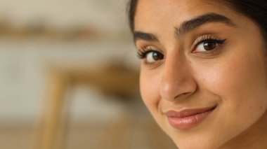 Kapalı yüz portresi gülümseyen, neşeli, mutlu, çekici, mutlu, sağlıklı, Hintli kadın ev içinde kameraya bakarak kozmetoloji dermatolojisine bakan Arap bayan.