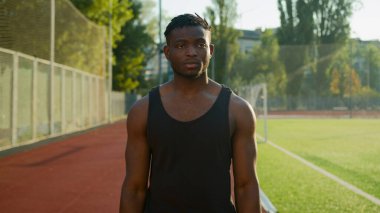 Sağlıklı aktif sporcu antrenmanı sabah stadyumunda ellerini uzatarak omuzlarını gerdirerek ısınma egzersizi erkek sporcu Afrikalı Amerikalı spor sporcusu açık havada spor yapıyor.