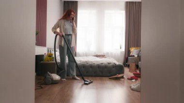 Stresli kadın sinirli Kafkasyalı kız meşgul ev kadını deli ev hizmetçisi elektrikli süpürge ev temizleme stresi yatak odasını temizleme dağınık ev temizliği cep telefonu tartışması