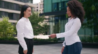 Afrikalı Amerikalı kadın, Asyalı Koreli kız iş kadınlarına iş kartı veriyor. Müşteri avukatı, çok ırklı kadın sigorta ortakları dışında iş dünyasının reklamını yapıyor.