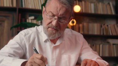 Kafkasyalı yaşlı adam not defteri yazıyor. Emeklilere, olgun erkek ofis işadamlarına evrak işleri planlıyorlar. Belge masasında çalışıyorlar.