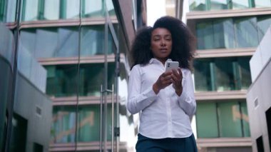 Afrika kökenli Amerikalı bir kadın cep telefonu kullanıyor. Akıllı telefon kullanıyor. İnternette mesajlaşmayı düşünüyor.