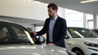 Düşünceli, düşünceli, beyaz bir adam, yeni bir araba seçen yeni bir tüketici otomobil satın almaya karar verdi, erkek otomobil alıcısı, sergi salonundaki adam, iş adamının kafası karıştı.