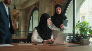 İş ortakları Arap erkek işadamı iş kadını tesettürlü Müslüman kadınlar danışman danışman danışman ofiste staj yapmasına yardımcı oluyor dizüstü bilgisayar işi projesi çok ırklı takım çalışması kurumsal eğitim