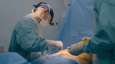 Üniformalı profesyonel tıbbi ekip doktorları klinikteki cerrahi operasyona yardım ediyorlar. Doktor doktor, hemşirelere şırınga anestezisi ve sağlık sigortası için yardım ediyor.