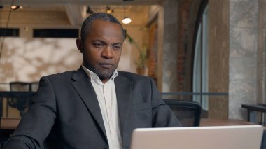 Orta yaşlı Afro-Amerikan girişimci dizüstü bilgisayarları tarıyor, bilgisayar yazıyor internet etnik iş adamı ofis işadamı iş adamı, bilgisayar başında masa işvereni ile çalışıyor.