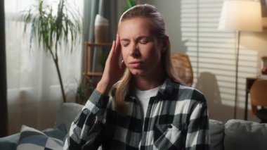 Evdeki portre endişeli, üzgün, düşünceli, üzgün, üzgün, hayal kırıklığına uğramış, beyaz kadın, migren ağrısı çekiyor. Kamera problemlerine bakıyor.