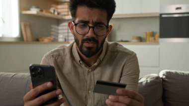 Stresli Arap Hindistanlı adam, üzgün erkek kart sahibinin cep telefonuyla internet üzerinden ödeme yapmasına hayal kırıklığına uğramış bankacılık uygulaması hatası para dengesi ve finansal limit eksikliği nedeniyle hayal kırıklığına uğramış.