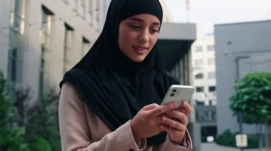 Şehirdeki kadın tesettürlü Müslüman kadın tesettürlü, akıllı telefon uygulamaları kullanarak mesajlaşan, internetteki uygulamalara cevap vermeyi düşünen iş kadını sohbet eden iş kadını.