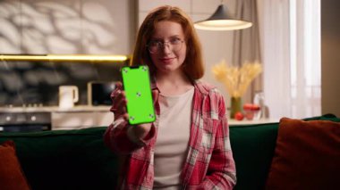 Gülümseyen Kafkasyalı genç kız, elinde akıllı telefon uygulaması, elinde yeşil ekran, cep telefonu, kroma, internet sitesi internet servis hizmeti sunumunu taklit ediyor.