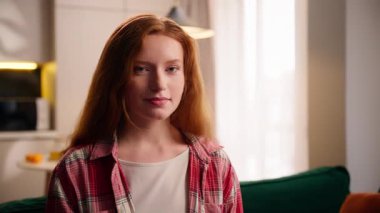 Sağlıklı bir şekilde gülümseyen beyaz bir kadın, genç bir bayan, gülümseyen bir kız, kameralı sağlık hekimine gülümseyen iyi bir ruh hali. Hafta sonu apartman tatiline bak. Oturma odasında dinleniyor.