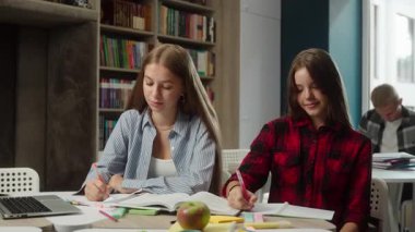Gülümseyen Kafkasyalı kızlar kız liseli kızlar lise öğrencileri birlikte okuyorlar. Masa başı üniversitesinde yazı dersi alıyorlar. İyi bir eğitimi onaylamak gibi kamera başparmaklarına bakıyorlar.