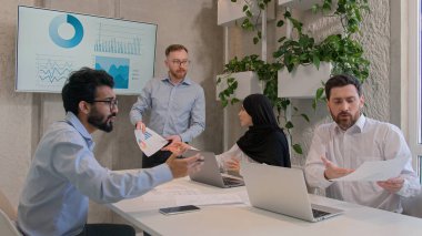 Emotional business team arguing at office discussing financial strategy graphics results diverse multiracial businessmen businesswoman dispute at corporate briefing solve issuess disagreement conflict