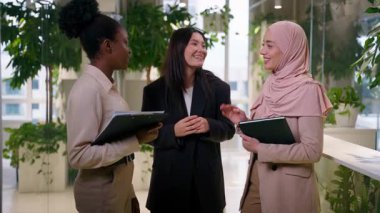 Ofisteki çok ırklı kızlar güler yüzlü kadın iş ortakları üç farklı iş kadını Asyalı Müslüman Afrikalı konuşma baş ağrısı sorunu yaşıyorlar