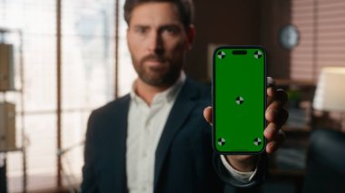 Ofisteki portre ciddi bir iş adamı orta yaşlı beyaz adam işadamı cep telefonu tutan adam yeşil ekran şablonu ile akıllı telefon ekran uygulaması gösteren bir model.