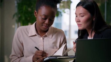 Çok ırklı iş kadınları iş ortakları iş arkadaşları, iş arkadaşları, Afrikalı Amerikalı lider, Asyalı Çinli stajyer, çok ırklı kız, kadın takım çalışması, ofiste ticaret laptopu yazmayı tartışırlar.