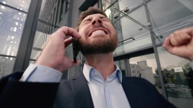 Neşeli, neşeli, heyecanlı, heyecanlı, akıllı telefon, erkek, yakın plan, girişimci kazanmayı kutluyor. İyi haber zaferi, Kafkasyalı iş adamı, şehirde cep telefonundan konuşan iş adamı.