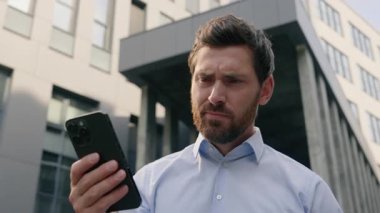 Ofisin yakınındaki üzgün, kaygılı erkek kötü haber okuyor. Reddedilmiş banka tebligatı sorunu var. Kafkasyalı iş adamı iş adamı şehirde cep telefonu kullanıyor.