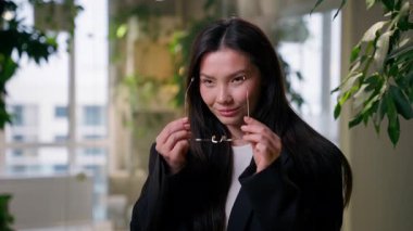 Asyalı stil sahibi iş kadını Koreli Çinli Japon öğrenci ofis müdürlüğünde gözlüklü moda kızı gözlüklü işkadını görüş açısı olan iş kadını kameraya bakıp gülümsüyor.