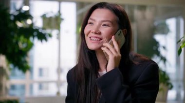 Mutlu Asyalı iş kadını cep telefonuyla konuşuyor Çinli Koreli iş kadını cep telefonunu arıyor ofiste Japonlarla sohbet ediyor sohbet ediyor sohbet ediyor sohbet ediyor sohbet görüşmesi yapıyor gülümsüyor danışmanlık