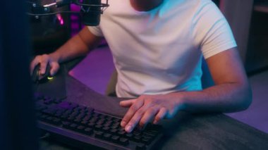 Neşeli, mutlu Arap, kulaklıklı, Latin, Hintli, gülümseyen, gülen, çizgi roman yazarı, klavye yazarı, blog yazarı, video blogcu, evdeki neon kameraya bakıp bilgisayar bilgisayarı çalıyor.