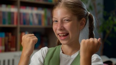 Mutlu, mutlu, küçük, beyaz kız öğrenci öğrenci öğrenci öğrenci öğrenci öğrenci, kameraya bakan kız öğrenciyi. Kapalı alanda başarılı bir sınıf eğitimi alabilmek için yumruk tokuşturarak harika bir haber kutluyor.