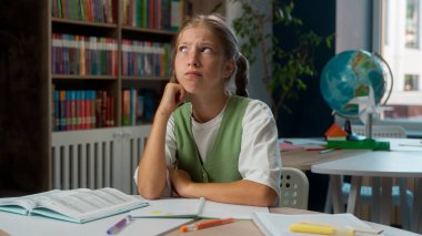 Düşünceli Kafkasyalı küçük kız çocuğu okul çocuğu öğrenci öğrenci zor bir sınav sınavı çözmeyi düşünüyor Eureka parmak kaldırma, kütüphanede çözüm bulma fikri.