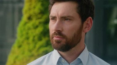 Şehir merkezindeki açık havada erkek portresini kapat. Orta yaşlı, beyaz, yetişkin, sakallı, iş adamı işveren, iş adamı. Başını çevirip kameraya bakarken mutlu bir şekilde gülümse.