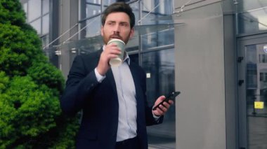 Ofis yakınındaki erkek müdür kahve içerken rahatlamış hayal kuruyor sakin sakin bakıyor cep telefonu beyaz adam işveren işadamı işe geç kalıyor.