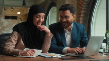 Erkek, kadın, Arap, erkek, kadın, tesettürlü, erkek, erkek, iş kadını, iki mutlu iş arkadaşı, yöneticiler pazarlama grafiklerini analiz eden, dizüstü bilgisayarda yazı yazan iki iş arkadaşı.