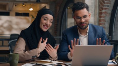 İki iş arkadaşı ofis kafesinde şirket işlerini tartışıyor. Çok ırklı erkek çalışanlar, Hintli erkek Müslüman kadın tesettürlü çeşitli iş kadınları dizüstü bilgisayarlar yazıyor.