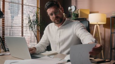 Stresli Kafkasyalı erkek yönetici, yönetici, iş adamı, yorgun işadamı, CEO, ofiste çalışan, dizüstü bilgisayarda çalışan, esneme sorunu yaşayan, kahve enerjisi bardağı işiyle uğraşan biri.