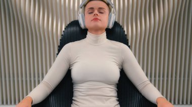 Kafkas kadın oyuncu sanal gerçeklik gelecekteki teknoloji neon stüdyo kızı iş kadını koltukta kablosuz kulaklık takarak rahatla müzik dinle müzik aleti ses rahatlatıcı