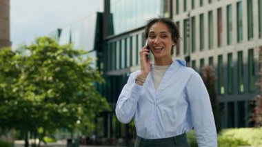 Mutlu, gülümseyen, Afro-Amerikan iş kadını, kadın, kadın, işveren, şehirde yürüyen akıllı telefon görüşmeleri, uzak mesafelere giden cep telefonları, açık hava iletişimi.