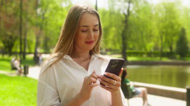 Avrupalı bir kadın cep telefonu, akıllı telefon teknolojisi, mesajlaşma, sosyal medyada mesajlaşma, kız ağlarına göz atma, park aleti bağımlılığı, internet bağlantısı, şehirli iş kadını.
