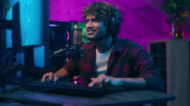 Heyecanlı Arap Latin erkek siber spor flamalı bilgisayar oyunu oyuncusu web mutlu adam zafer kazanan yarışma bağımlısı erkek mikrofon yayıncısı blogcu e-spor bilgisayar oyununun keyfini çıkarın