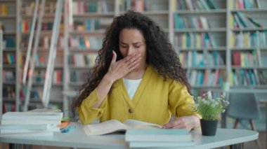 Hindistanlı İspanyol kadın öğrenci öğretmen kitap okuyor, kitap okuyor, esniyor, kütüphane kütüphanesi kolej sınavı uykusuzluk eğitimi alıyor, ders hazırlanıyor, bayan akademisyen.