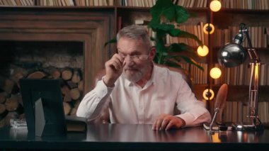 Kameralı başarılı iş adamına bakan yaşlı beyaz bir adam. Gözlüklerini çıkarıyor. Sağlıklı vizyon işi.