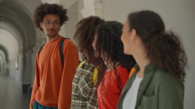 Üniversite koridorundaki grup mutlu çeşitlilik öğrencileri gülümseyip gülümsüyor üniversitedeki dört çok ırklı Afrikalı Amerikalı erkekle Arap İspanyol kadın kızlar kameraya olumlu bakıyor