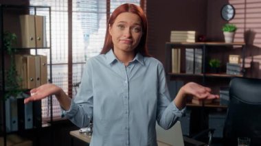 Beyaz kadın, iş kadını, ofis kamerasına bakan iş kadını. Yanıtı bilmiyor, omuz silkme, omuz silkme, hiçbir şeyden haberi yok. Cevap yok.