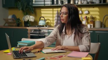 Latin Latin kadın konsantre olmuş etnik kız liseli kız öğrenci gen z genç serbest çalışan iş kadını ev mutfağında notlar yazıyor online sınıf video dersi yazıyor ev ödevi yazıyor
