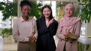 Gülümseyen çeşitli iş kadınları Afrikalı Müslüman Asyalı çok ırklı mutlu kızlar iş ortağı üç kadın alkışlayan alkışlayan alkışlayan alkışlayan alkışlayan alkışlayan alkışlayan alkışlayan takım çalışması