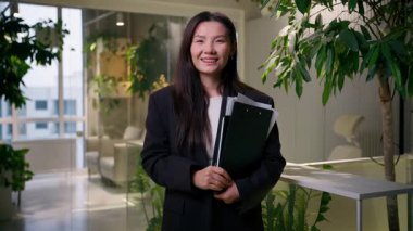 Asyalı mutlu etnik iş kadını Çinli Koreli Japon kız yönetici avukat satış danışmanı ofisteki klasör belgelerini kapalı, olumlu iş kadını gülüşü dişli diş telleri